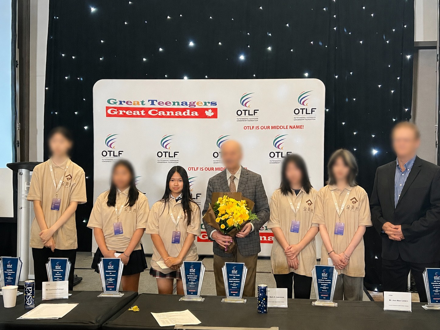 Mia on an award ceremony stage holding a bouquet of flowers