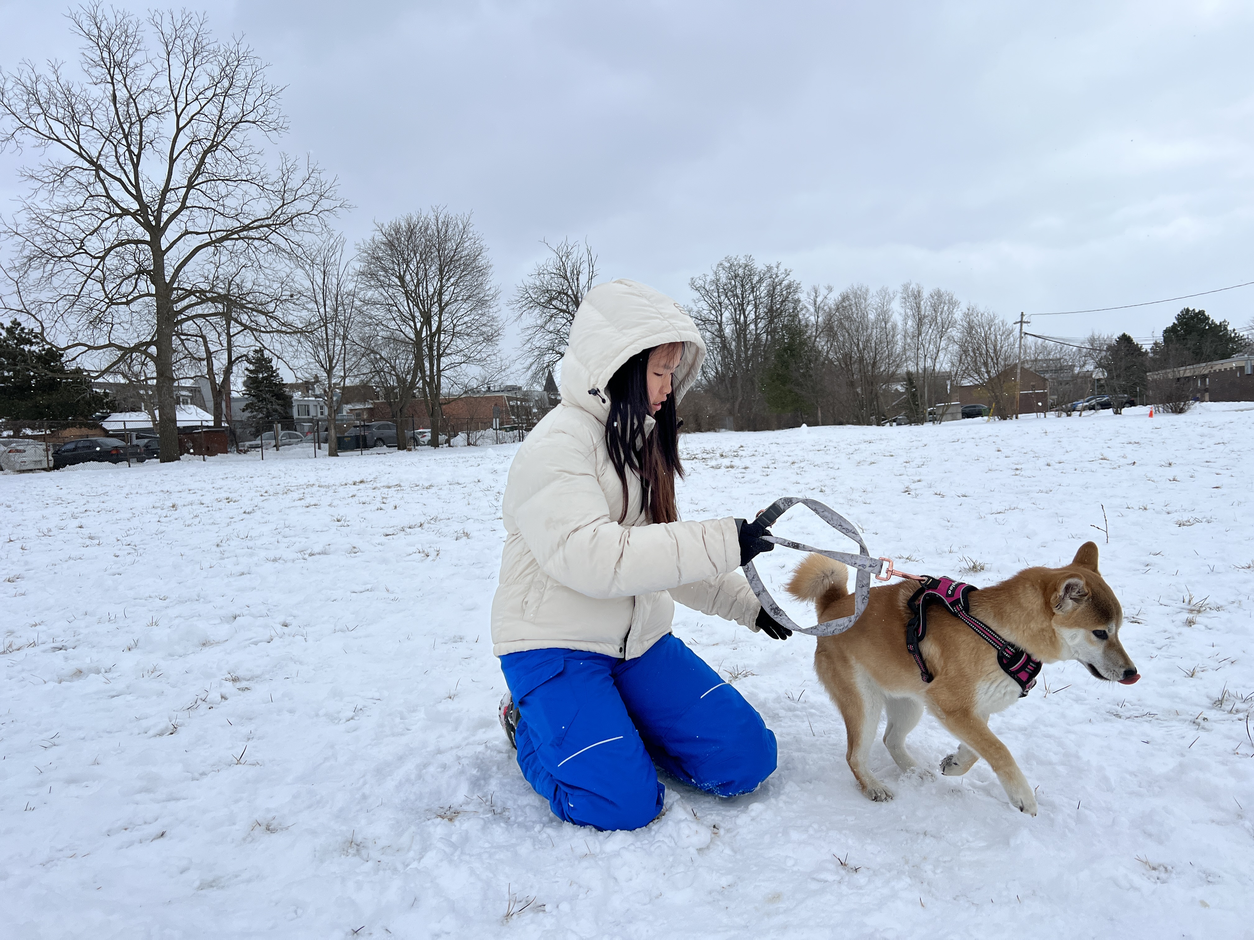 Mia kneeling with her Shiba Inu in a snowy field