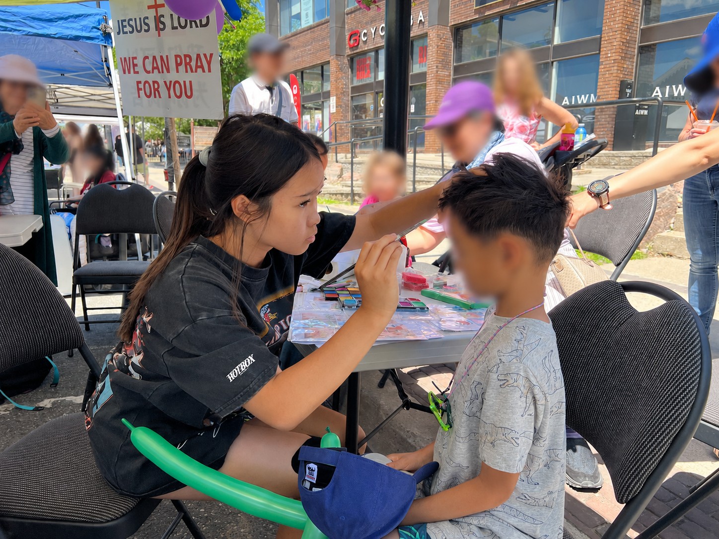 Mia face-painting a child's face at an outdoor community event