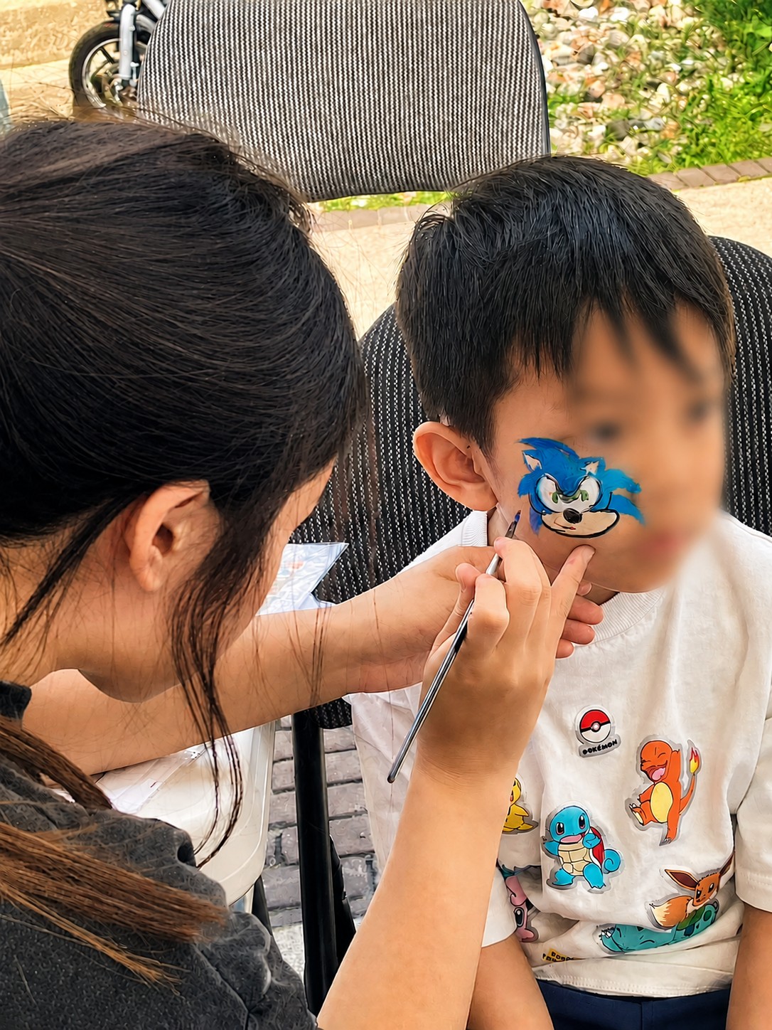 Mia face-painting a Sonic the Hedgehog design on a child's face