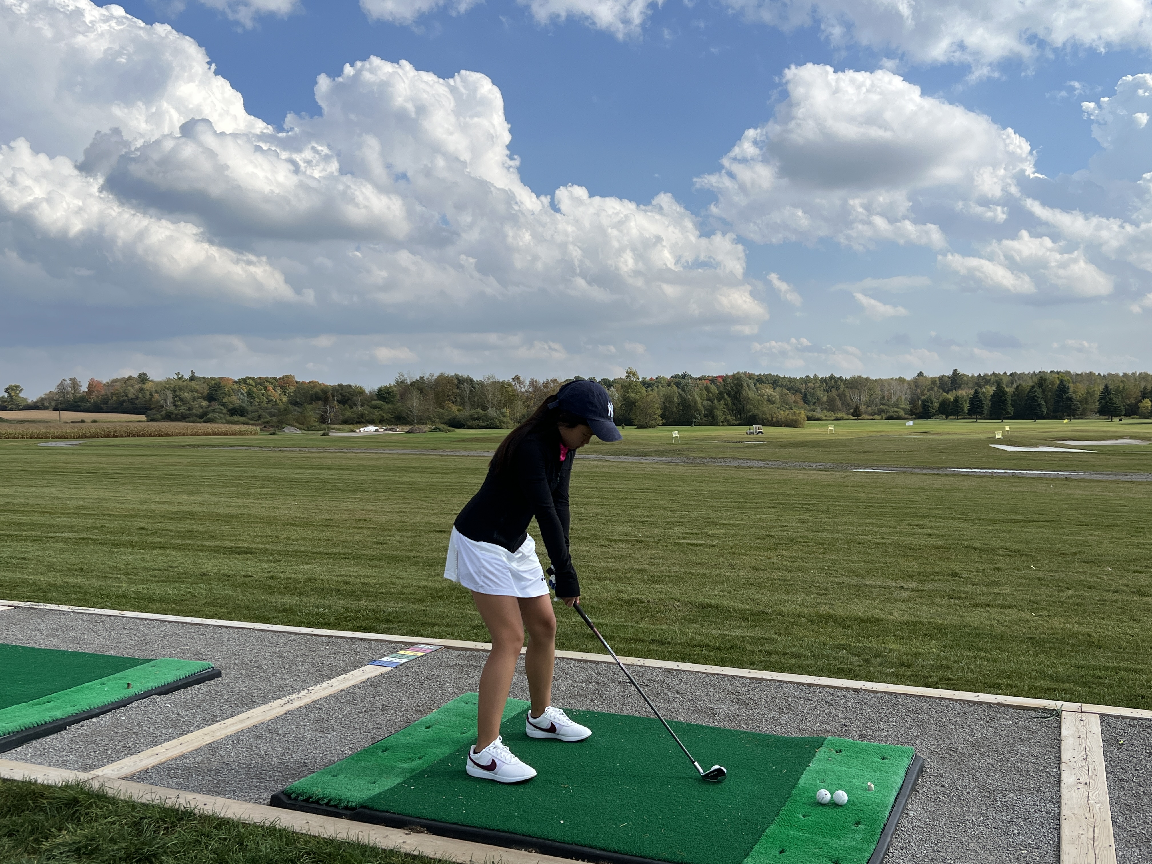 Mia completing a golf swing at a driving range