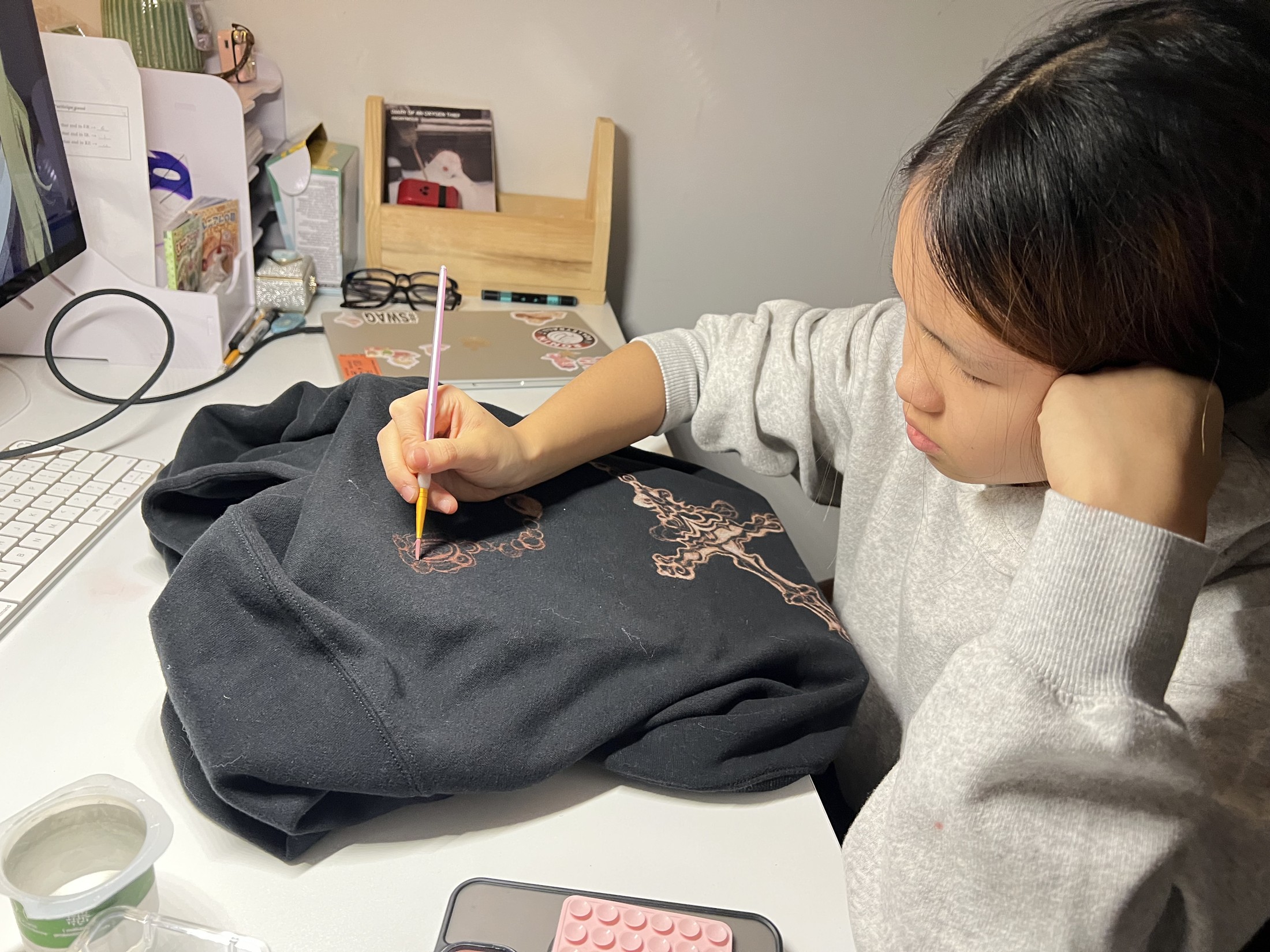 Mia hand-painting a design onto a hoodie