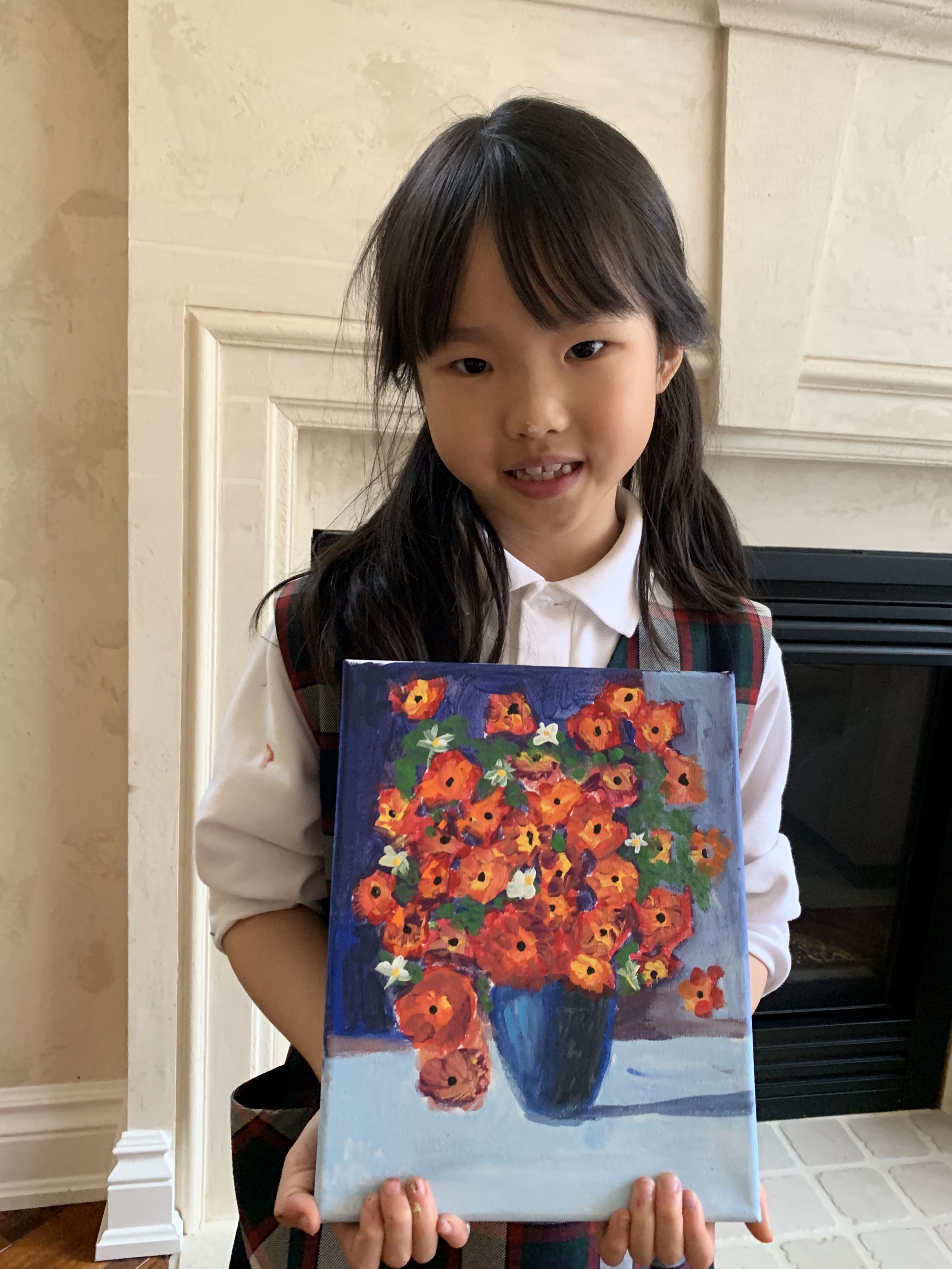A young Mia smiling and holding her still-life painting of orange flowers in a blue vase