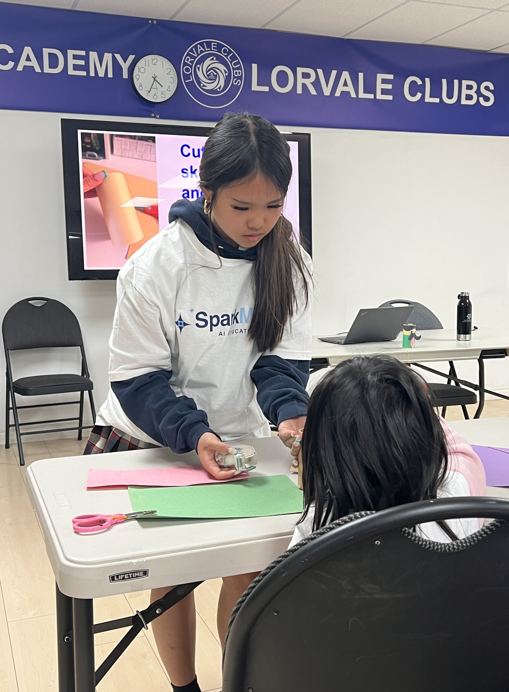 Mia leading a paper-craft activity with a young child at a community event