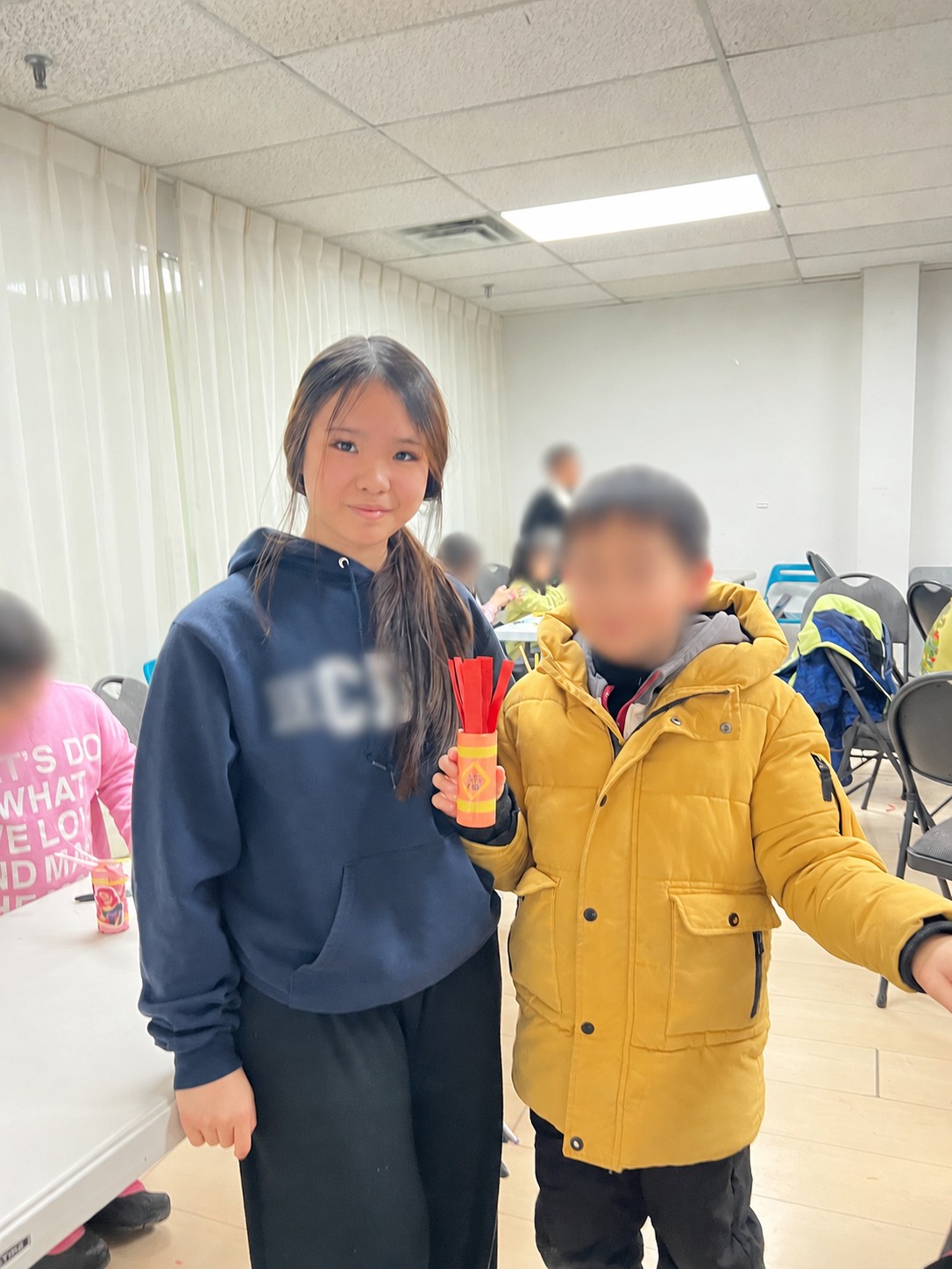 Mia posing with a young boy holding a red paper craft