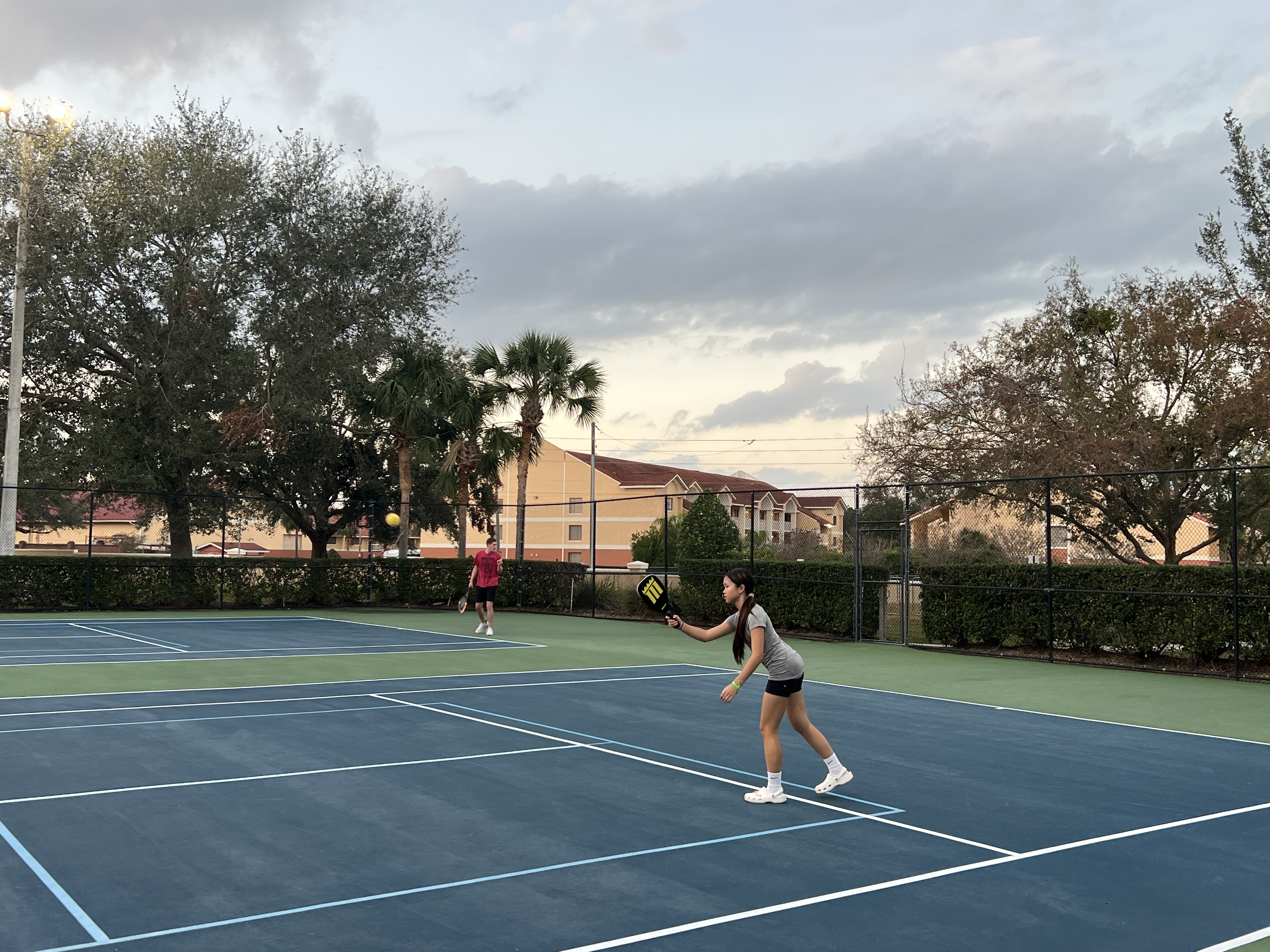 Mia playing pickleball on an outdoor court at dusk