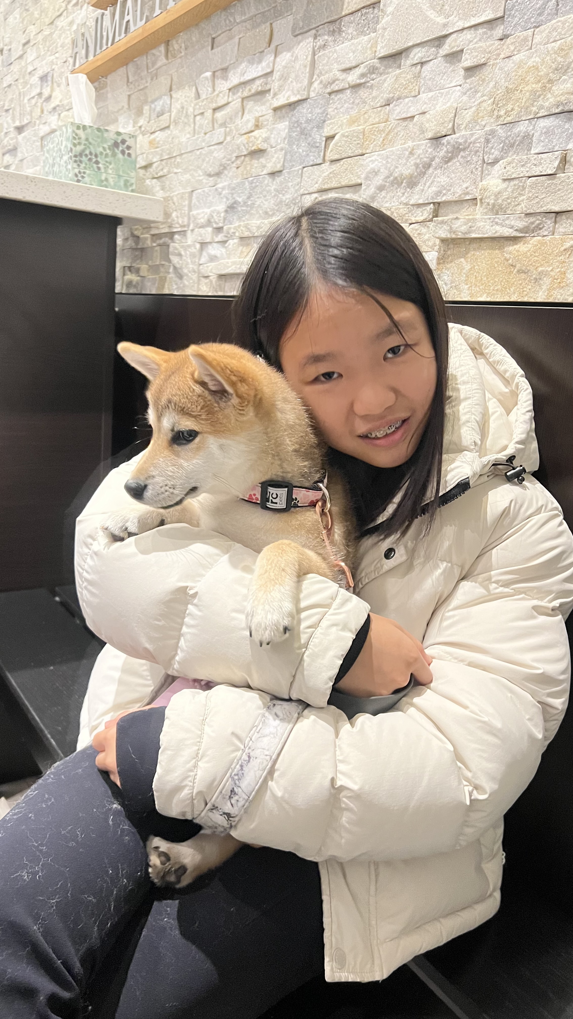 Mia holding her Shiba Inu puppy at a veterinary clinic